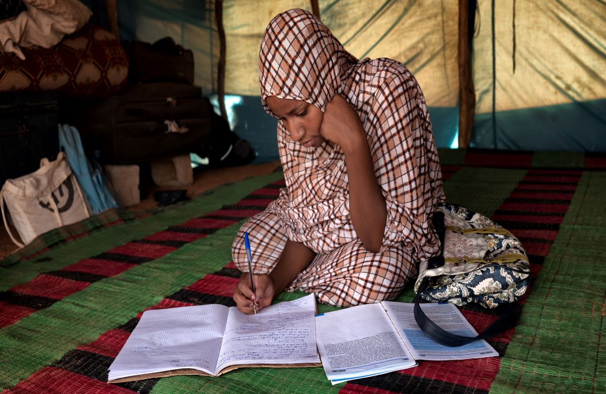 A young girl doing homework writing in an open folder